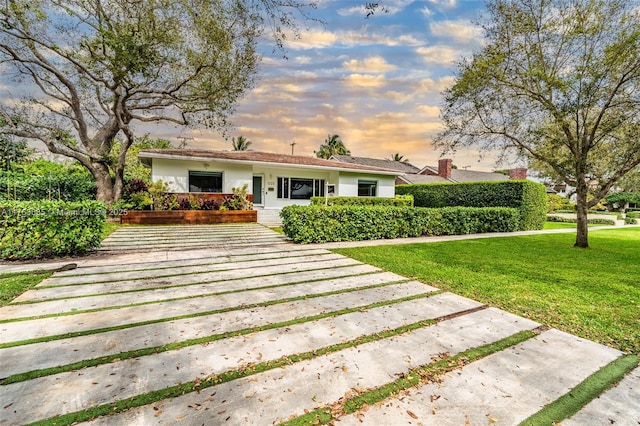 ranch-style home with a lawn and stucco siding