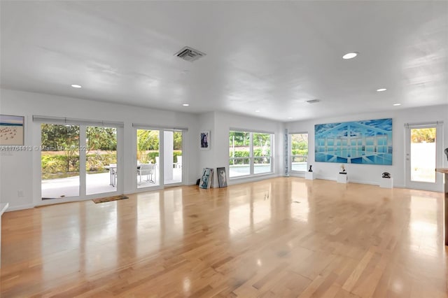 unfurnished living room with baseboards, light wood finished floors, recessed lighting, and a wealth of natural light
