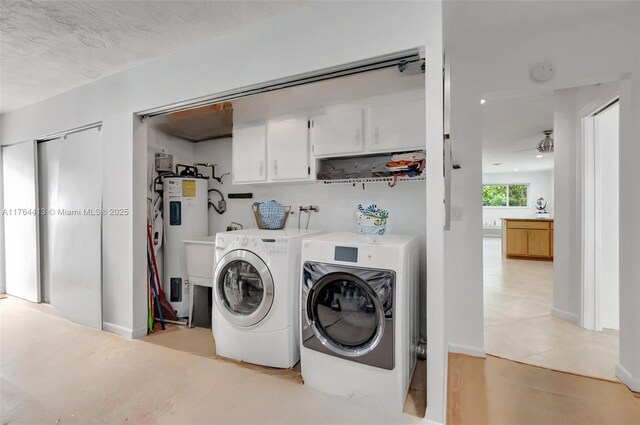 washroom featuring electric water heater, light tile patterned floors, cabinet space, and washing machine and clothes dryer