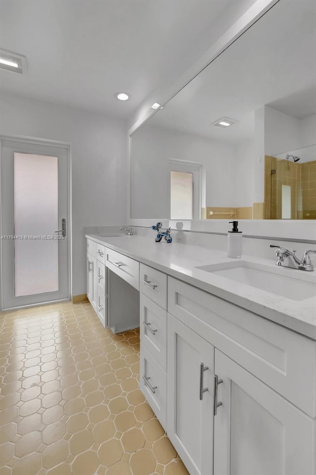 full bathroom with double vanity, recessed lighting, a tile shower, and a sink