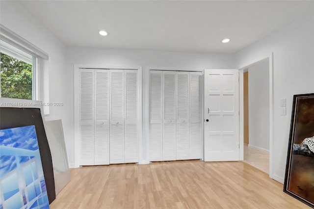 unfurnished bedroom with multiple closets, baseboards, recessed lighting, and wood finished floors