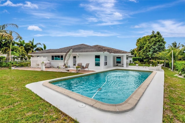 exterior space with stucco siding, a patio area, an outdoor pool, and a yard