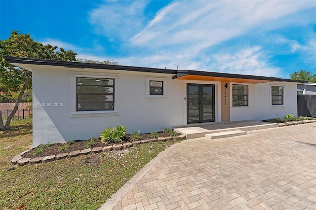 view of front of house featuring stucco siding, french doors, and fence