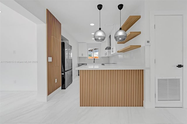 kitchen with visible vents, a peninsula, open shelves, freestanding refrigerator, and light countertops