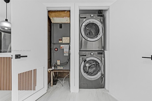 laundry area featuring heating unit, laundry area, and stacked washer and dryer