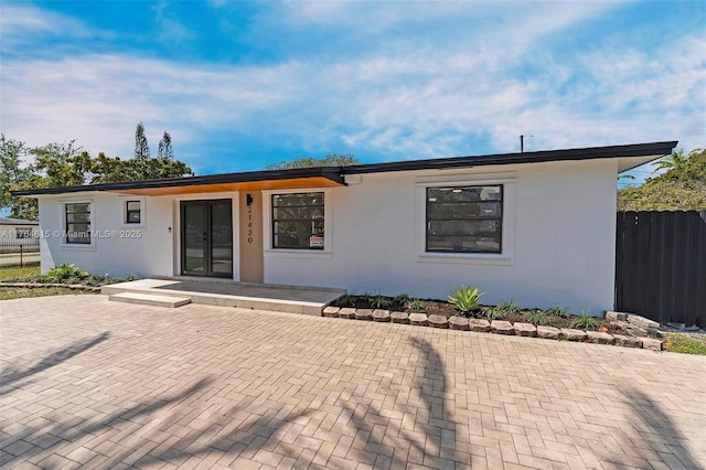 view of front facade with french doors, fence, and stucco siding