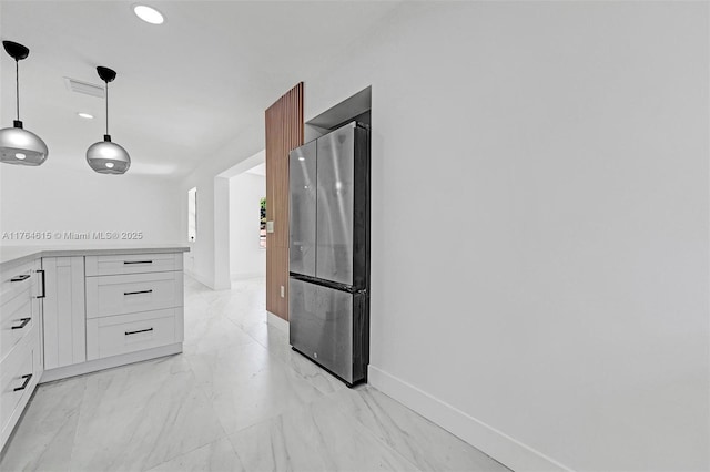 kitchen with marble finish floor, freestanding refrigerator, white cabinets, light countertops, and baseboards