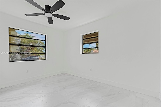 unfurnished room with marble finish floor, a ceiling fan, and baseboards