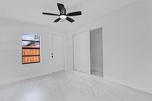 unfurnished room featuring baseboards, marble finish floor, and a ceiling fan
