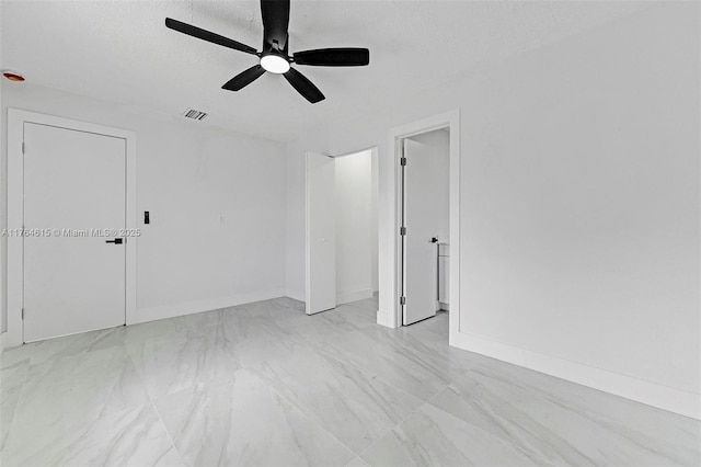 empty room with visible vents, marble finish floor, a ceiling fan, a textured ceiling, and baseboards