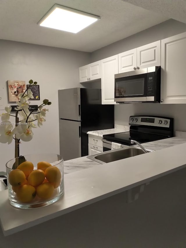 16465 NE 22nd Ave Unit 114, North Miami Beach, FL 33160 - kitchen featuring white cabinetry, light countertops, a sink, and appliances with stainless steel finishes