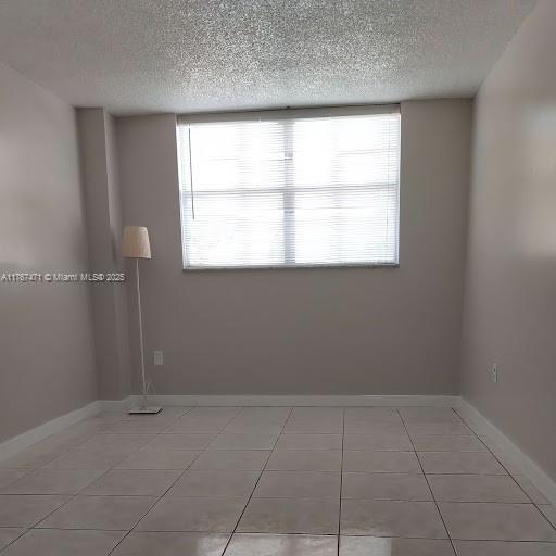 16465 NE 22nd Ave Unit 114, North Miami Beach, FL 33160 - empty room featuring plenty of natural light, baseboards, and a textured ceiling