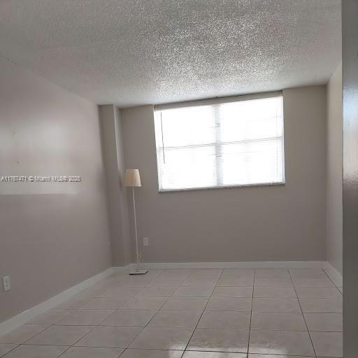 16465 NE 22nd Ave Unit 114, North Miami Beach, FL 33160 - spare room featuring light tile patterned flooring, baseboards, and a textured ceiling