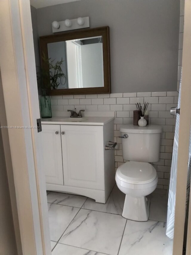 16465 NE 22nd Ave Unit 114, North Miami Beach, FL 33160 - bathroom with marble finish floor, toilet, vanity, and a wainscoted wall