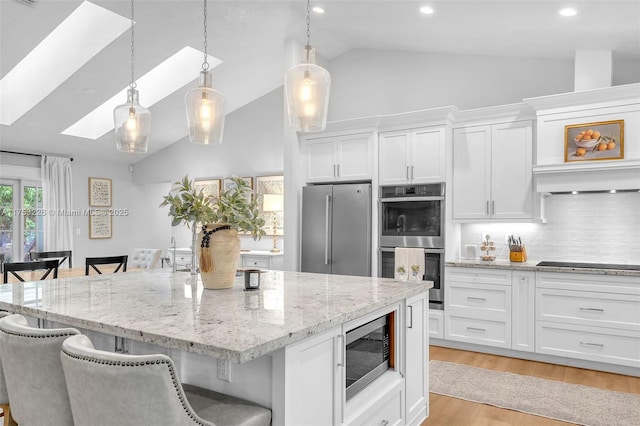 kitchen with white cabinetry, light wood-style flooring, stainless steel appliances, and a breakfast bar area