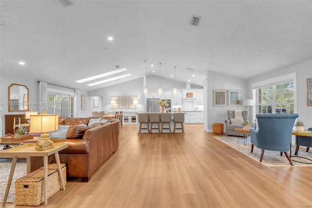 living room featuring recessed lighting, visible vents, lofted ceiling with skylight, and light wood-type flooring