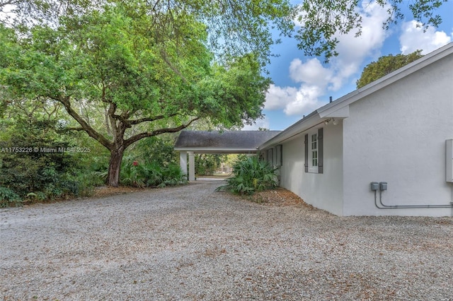 view of home's exterior with gravel driveway and stucco siding