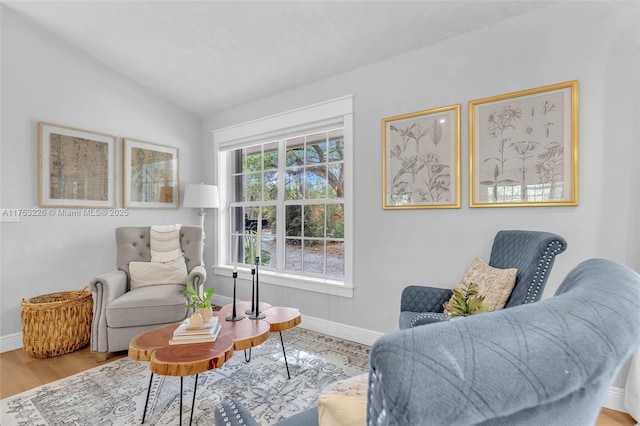 sitting room with baseboards, lofted ceiling, and wood finished floors
