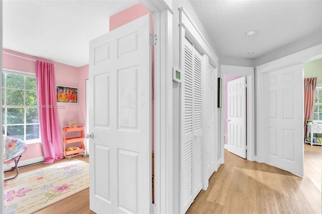hallway with a textured ceiling and light wood-type flooring