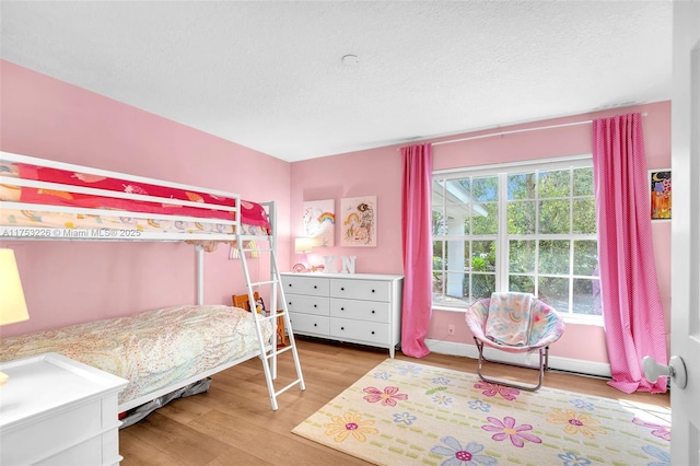 bedroom with a textured ceiling, baseboards, and wood finished floors