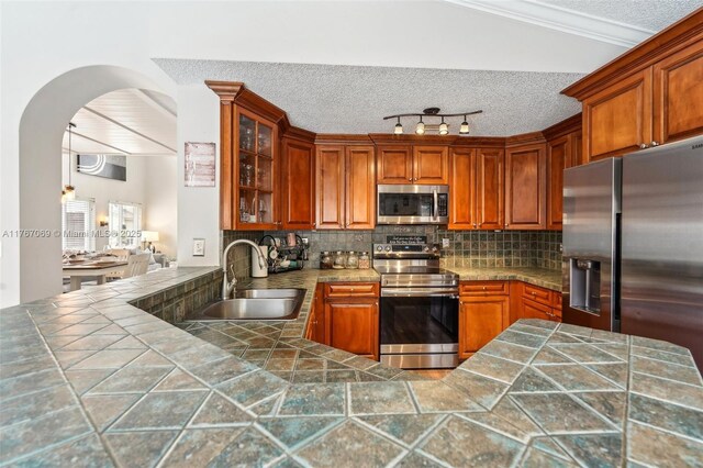 5081 SW 154th Pl, Miami, FL 33185 - kitchen featuring stainless steel appliances, a sink, arched walkways, glass insert cabinets, and ornamental molding