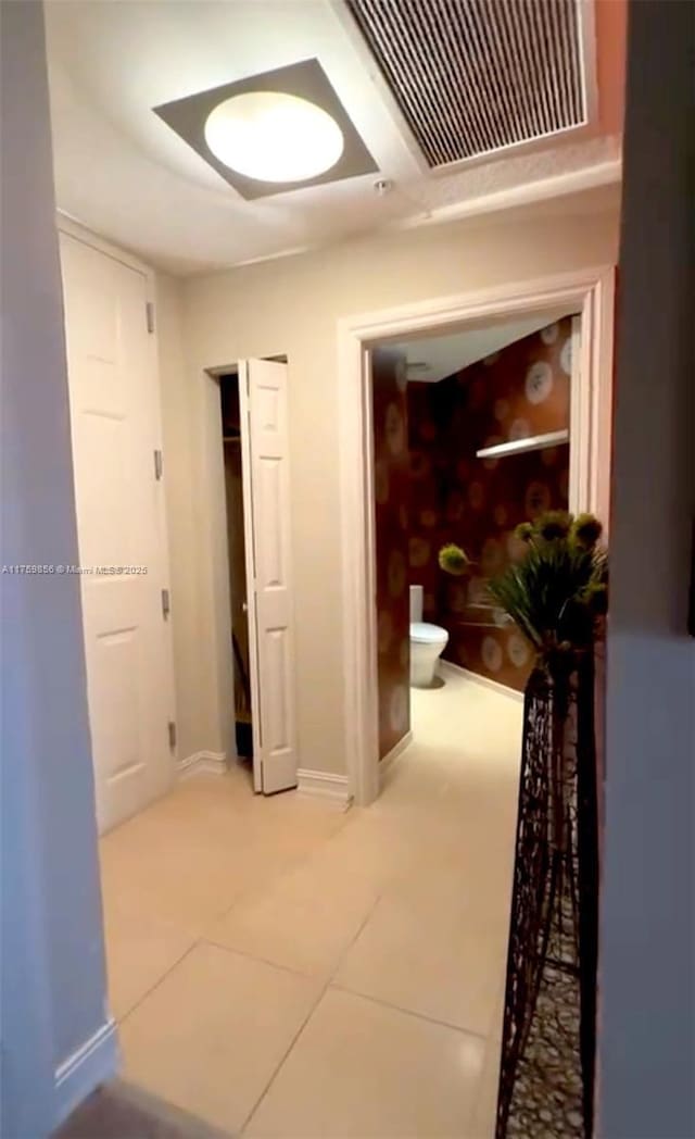 hallway featuring baseboards, tile patterned flooring, and visible vents