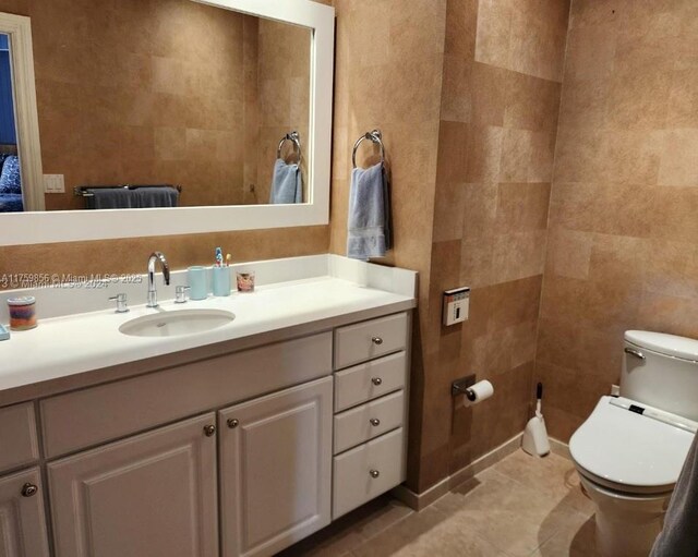 bathroom with tile walls, toilet, vanity, and tile patterned floors