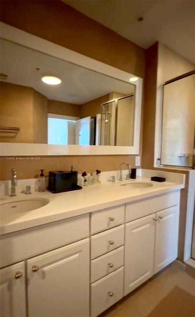 bathroom featuring a shower stall, double vanity, and a sink