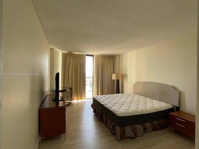 20281 E Country Club Dr Unit 810, Aventura, FL 33180 - bedroom featuring a wall of windows, light wood-type flooring, and a textured ceiling