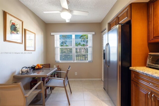 12900 SW 13th St Unit 211E, Pembroke Pines, FL 33027 - kitchen with appliances with stainless steel finishes, brown cabinetry, light stone countertops, light tile patterned floors, and recessed lighting