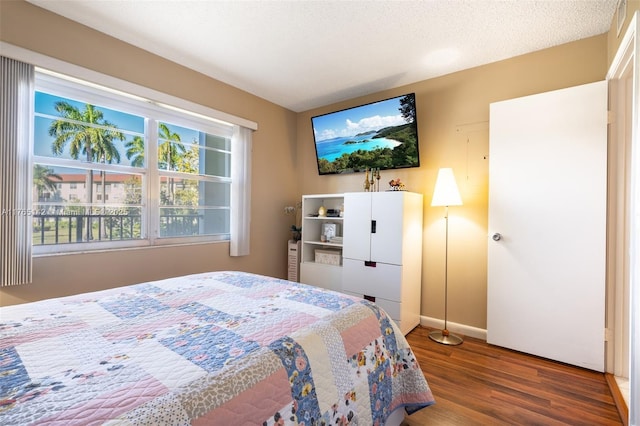 bedroom featuring a textured ceiling, baseboards, and wood finished floors