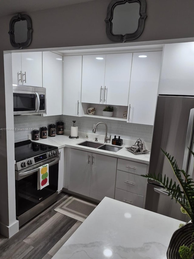 kitchen featuring a sink, stainless steel appliances, white cabinets, and light countertops