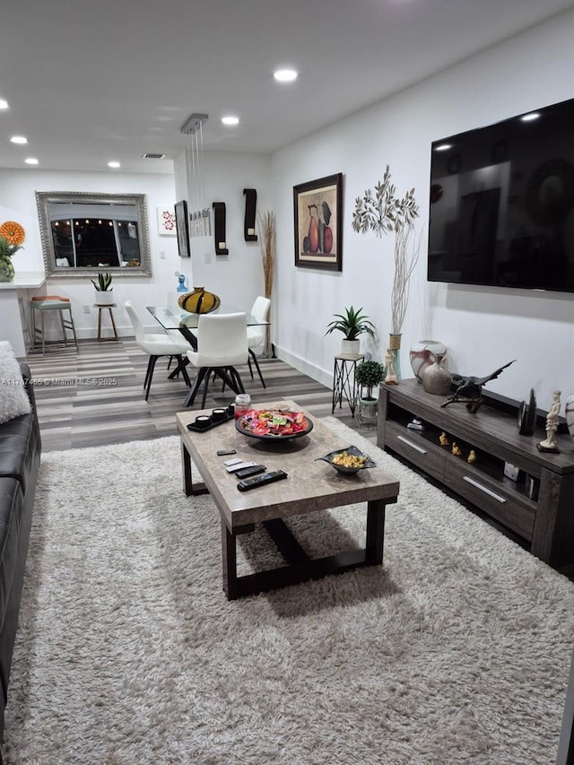 living room with wood finished floors, recessed lighting, visible vents, and baseboards