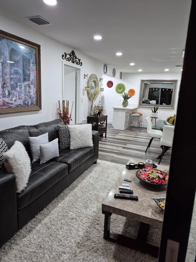 living room with visible vents, recessed lighting, and wood finished floors