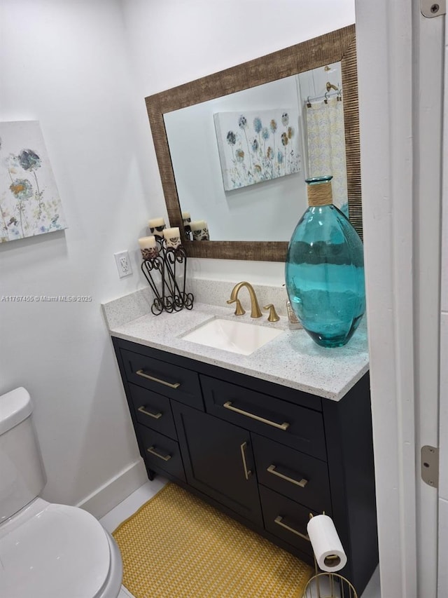 bathroom with baseboards, toilet, and vanity
