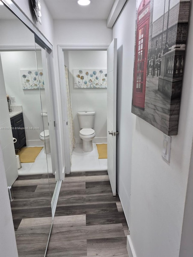 bathroom with vanity, toilet, wood finished floors, and baseboards