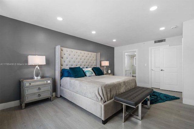 bedroom with visible vents, ensuite bathroom, wood finished floors, recessed lighting, and baseboards