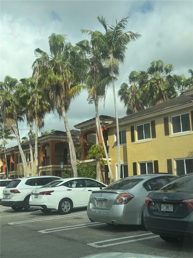 view of front of home with stucco siding, a tiled roof, and uncovered parking
