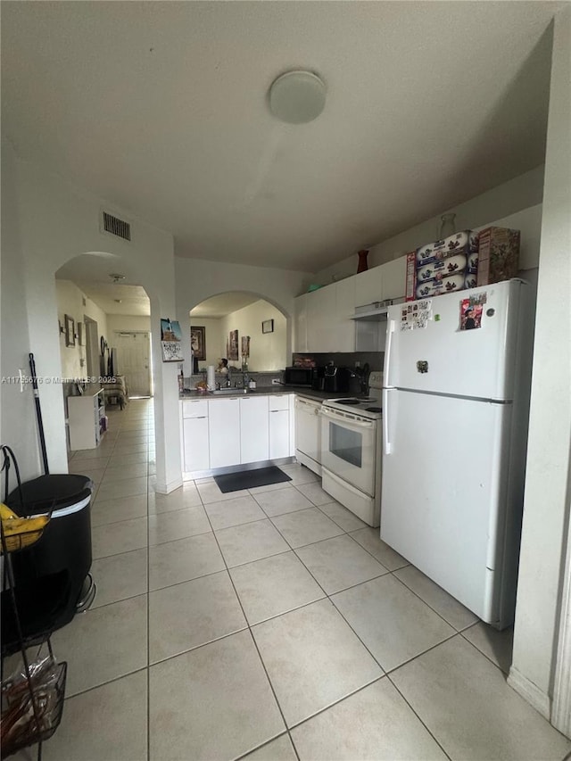 kitchen with white appliances, white cabinets, light tile patterned floors, and visible vents