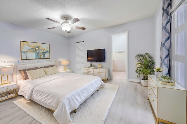 bedroom featuring ceiling fan, ensuite bathroom, and light wood finished floors