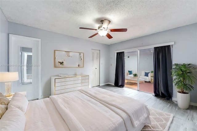 bedroom with access to exterior, baseboards, ceiling fan, light wood-type flooring, and a textured ceiling