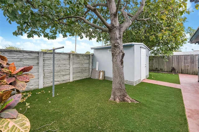 view of yard featuring an outbuilding, a storage unit, and a fenced backyard