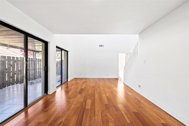 empty room featuring visible vents, stairway, baseboards, and wood finished floors
