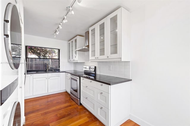kitchen featuring dark countertops, stainless steel electric stove, a sink, fridge, and wall chimney exhaust hood