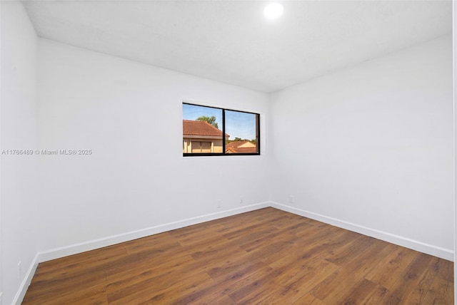 unfurnished room with baseboards and wood finished floors