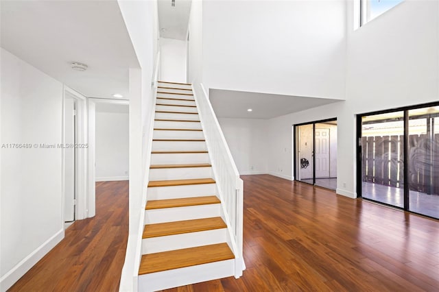 stairs with plenty of natural light, wood finished floors, and baseboards