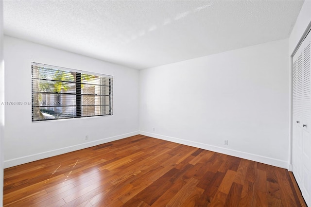 unfurnished room with baseboards, wood-type flooring, and a textured ceiling