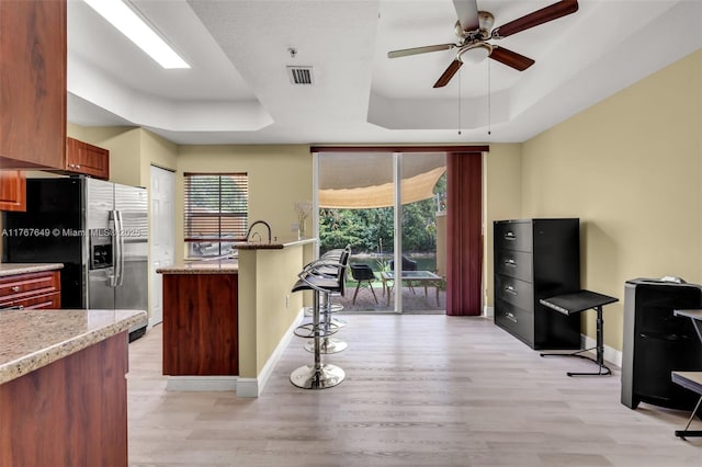 983 SW 143rd Ave Unit 1403, Pembroke Pines, FL 33027 - kitchen with a raised ceiling, stainless steel refrigerator with ice dispenser, light wood finished floors, a breakfast bar, and ceiling fan