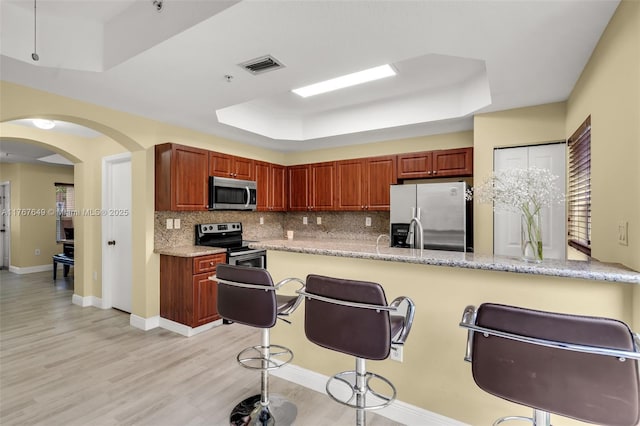 983 SW 143rd Ave Unit 1403, Pembroke Pines, FL 33027 - kitchen featuring stainless steel appliances, a tray ceiling, decorative backsplash, and a breakfast bar area