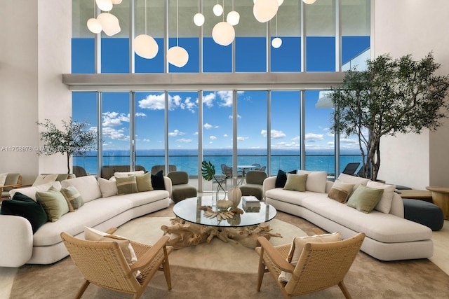 living area with a wall of windows, a high ceiling, a healthy amount of sunlight, and a water view